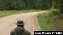 Un polițist de frontieră rus se uită la omologul său estonian în interiorul secțiunii „Cizma Saatse” a graniței comune a celor două țări.