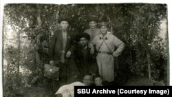 Кыргызстан НКВДсынын кызматкери Иса Кураманов (оңдо) Кыргызстандан сүргүнгө айдалгандар менен. Хлебодаровка, 1931-жыл. 