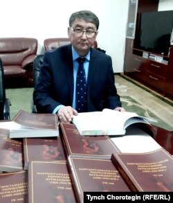 Профессор Төлөбек Абдырахманов «Кыргызстандагы саясий репрессиянын курмандыктары: (1920–1953-жылдар)” деген он томдуктун мукабаларын көрсөтүүдө.