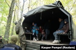 Migranții irakieni, într-un camion militar după ce aceștia au fost prinși de către polițiștii de frontieră și ofițerii de poliție în Hajnowka, Polonia 14 octombrie 2021