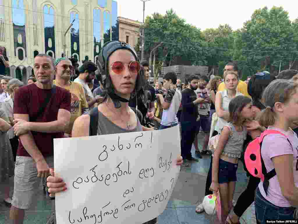 Танкистің киімін киген азамат грузин тілінде "Гахария, бүгін - менің туған күнім. Отставкаға кетші. Сыйлығың болсын" деген жазуы бар плакат ұстап тұр. Тбилиси, 3 шілде 2019 жыл.