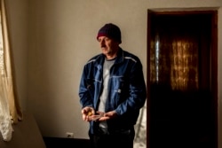 Huso Halilović drži u rukama sat i češalj koji su jedina uspomena na njegovog oca koji je ubijen tokom genocida u Srebrenici.