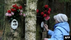 A woman cleans a plaque for a victim of Stalin's purges at a memorial on the outskirts of St. Petersburg.