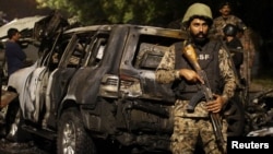 یو امنیتي سرتېری په کراچۍ کې د چینايي انجینرانو پر ګاډي د اکتوبر تر شپږمې برید وروسته د پېښې په ځای کې ولاړ دی. 