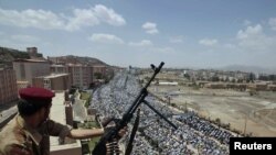 Йемендин борбору Санаа шаарында өкмөттүк күчтөрдүн жоокери оппозициячыл жыйынды байкап карап турат. 2011-жылдын 3-июну, түшкө чейинки маал.