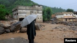 د بونېر په بیشوڼۍ کلي کې یو سړی د باران او سېلاب له وجې اغېزمنو ودانیو ته ګوري - د اګست ۱۸مې انځور.