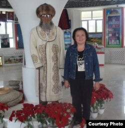 Назгүл Турдубаева азыркы КЭРдин Кызыл-Суу Кыргыз автоном облусуна караштуу Ак-Чий ооданындагы Кара-Булак айылында жайгашкан Жусуп Мамайдын музейинде маркум манасчынын момдон жасалган айкелинин жанында. 30.7.2015.