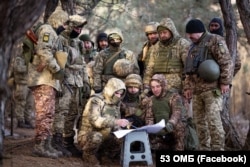 Soldații din Brigada 53 Mecanizată a Ucrainei pozează pentru o replică a imaginii în ianuarie 2024.