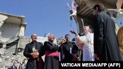 پوپ فرانسېس د عراق په موصل کې د جګړو پر مهال د یوې ړنګې کلیسا له ودانۍ سره نېږدې د سولې سپینه کوتره ازادوي - د ۲۰۲۱ز کال د مارچ اوومې انځور.