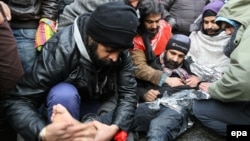 Asylum seekers from Afghanistan rub a fellow protester's feet against the cold as they gather to protest at the 'Grand Place' in Mons, Belgium. (file photo) 