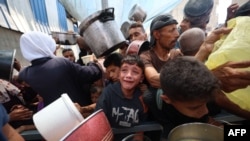 Copii palestinieni așteaptă să primească mâncare la un punct de distribuție din Nuseirat - Fâșia Gaza, 11 iunie 2025