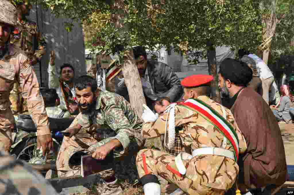 Soldiers and a Shi'ite Muslim cleric (right) sitting close to the ground seeking cover at the scene of the attack.