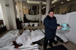 Колишній міліціонер Володимир Голоднюк тримає шолом свого сина Устима Голоднюка, який загинув на Інститутській вулиці в Києві 20 лютого 2014 року. У шоломі кульовий отвір. На підлозі в холі готелю «Україна» лежать тіла убитих в цей день протестувальників. Голоднюк тільки що впізнав серед них свого сина