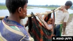 Бангладешке качкан рохинжа мусулмандары карыган кемпирди көтөрүп баратышат.  3-сентябрь, 2017-жыл