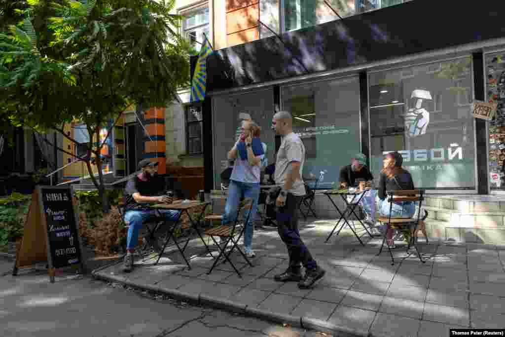 Жена ги покрива ушите додека руски дрон лета над населба со продавници во градот Краматорск, на фронтовската линија. 10 септември 2025 година.