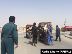 An Afghan policeman looks at civilians in Helmand.