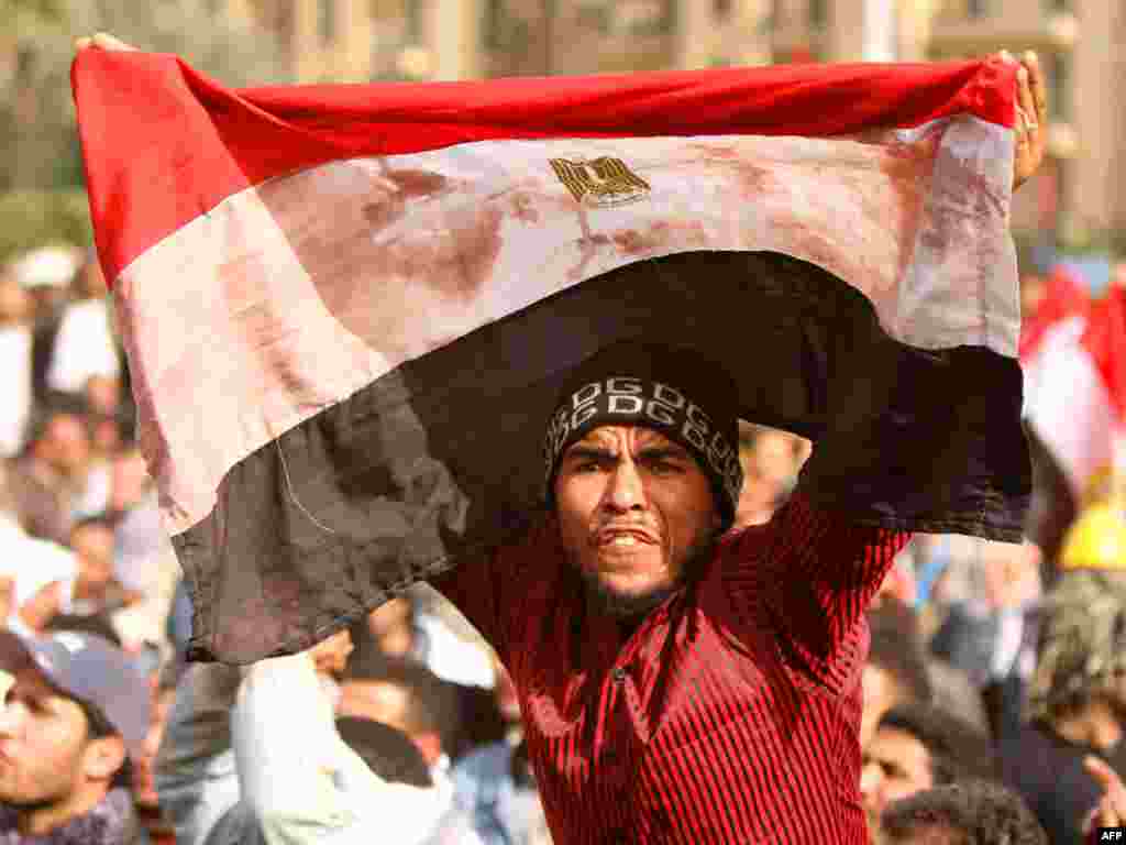 An antigovernment protester waves a bloodstained Egyptian flag in Cairo's Tahrir Square.