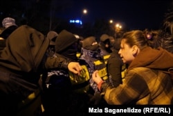 ნიღბიანები აქციის მონაწილე ქალების წინ, პროტესტის 67-ე დღე, "თბილისი მოლის" მიმდებარე ტერიტორია