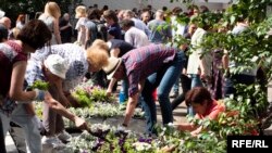 Oamenii plantează flori în timp ce participă la o ceremonie de deschidere a unei grădini publice în memoria jurnalistei Anna Politkovskaia