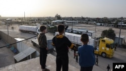 ბიჭები თვალს ადევნებენ სატვირთო მანქანებს, რომლებსაც ღაზის სექტორში ჰუმანიტარული დახმარება შეაქვთ. რაფაჰი, 26 ნოემბერი, 2023.