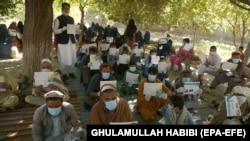 Afghans wait to receive cash distributed through an aid program in the Pachiragam Khogyani district of Nangarhar Province. (file photo)