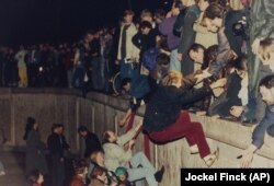 در این تصویر مربوط به ۱۰ نوامبر ۱۹۸۹، شهروندان غرب برلین به ساکنان بخش شرقی آن برای بالا رفتن از دیوار کمک می‌کنند
