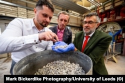 Cercetătorii ucraineni Oleksii Hunyak (stânga) și Taras Markiv (centru) și cercetătorul britanic Leon Black inspectează fragmente de beton reciclat în Leeds.
