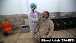 A health official conducts a COVID-19 test on a journalist in Peshawar on June 3.