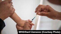 Врач маркирует палец мальчика после того, как ему сделали прививку во время дополнительных кампаний по иммунизации в ответ на вспышку кори. Фото: ВОЗ/Даниль Усманов