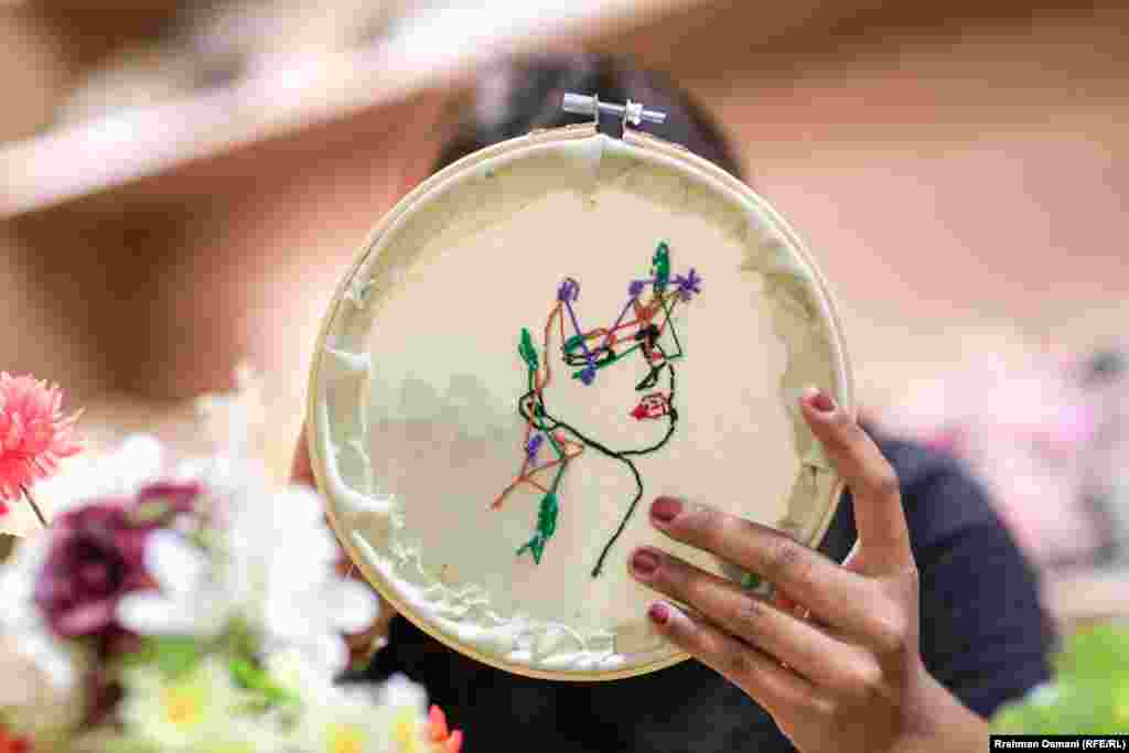 Me gjilpërë në dorë e penj shumëngjyrësh, ato mësojnë se si të zbukurojnë pëlhurën e vendosur në kornizat për qëndisje.