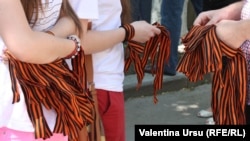 Membri ai Ligii tinerilor împart panglici bicolore negru oranj în centrul Chișinăului, 9 mai 2013 (arhivă).