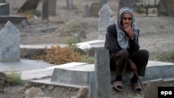 An elderly Afghan man sits at a grave in a graveyard of Afghan casualties of the Soviet war.