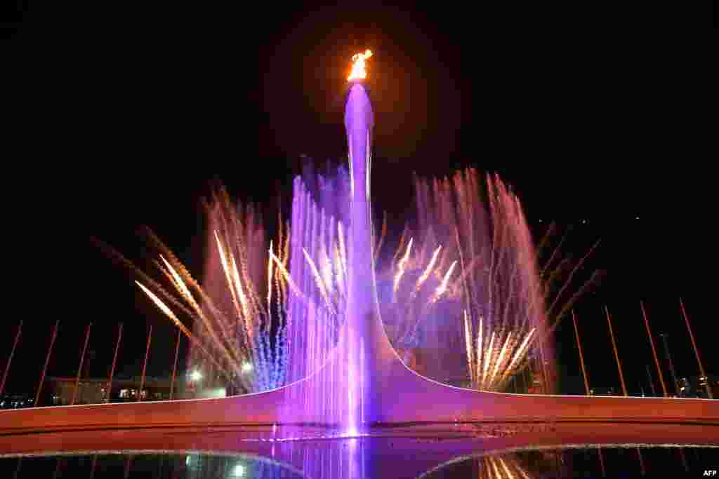 Fireworks explode behind the Olympic flame cauldron at the end of the opening ceremony. 