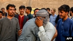 په کراچۍ کې یو افغان تر کډې بارولو مخکې له بل کس سره د مخه ښې پر مهال ژاړي - د اپرېل اتمې انځور. 