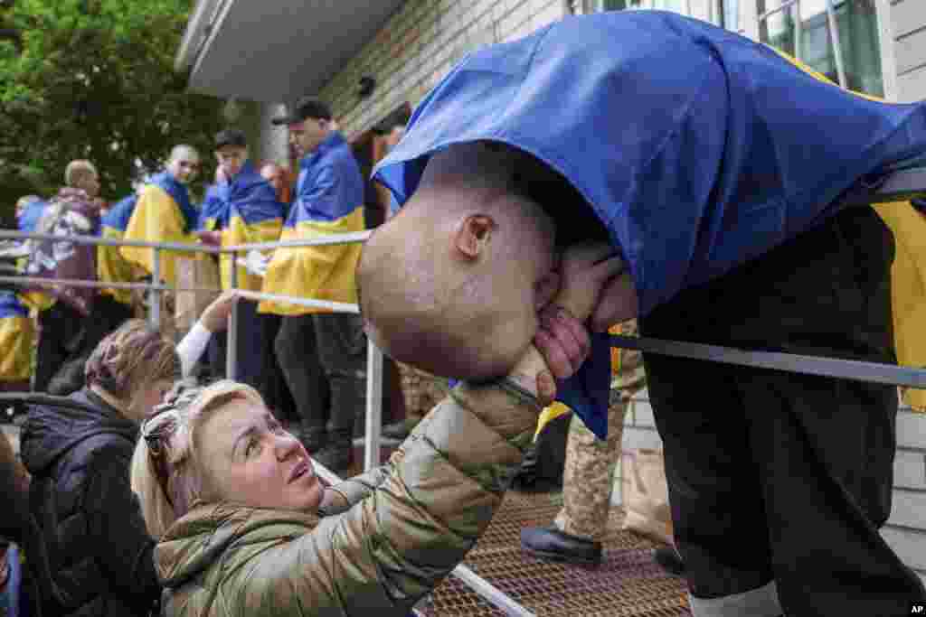 Аскердик туткандарды алмашуудан кийин үйүнө кайтып келген украиналык аскер аялдын колун өөп жатат. 6-май, Украина. 