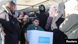 په خان یونس کېمپ کې یو ماشوم مرستندويه سامان کور ته وړي ـ د جنورۍ ۲۱ مې انځور.