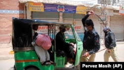 Police officers forcing a rickshaw driver to stop working during a nation-wide lockdown to curb the spread of the coronavirus in the southern city of Hyderabad in Sindh Province on April 3.