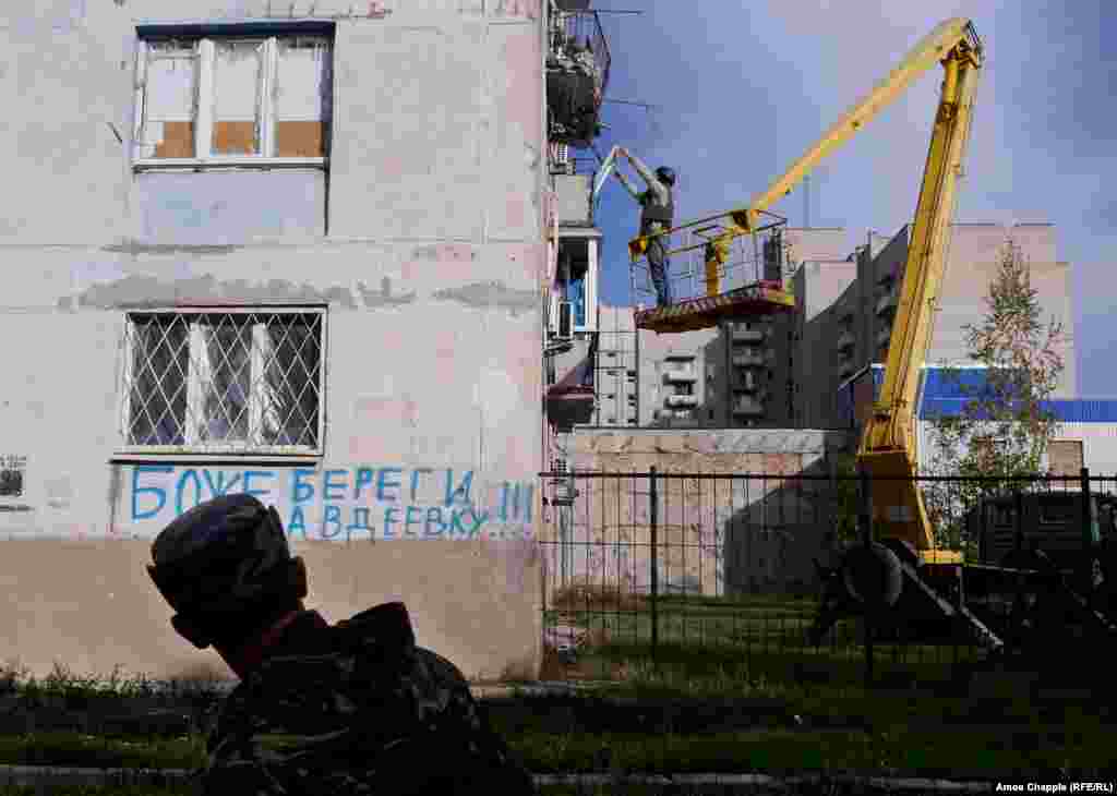 Поки ван Хелтен піднімається на своє робоче місце, український військовий проходить повз графіті: &laquo;Боже, борони Авдіївку&raquo;