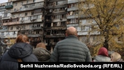 Area residents look over the aftermath of a Russian drone strike on a Kyiv apartment complex on October 26.