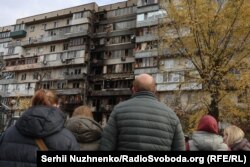 Stanovnici tog područja gledaju na posljedice napada ruske dron letjelice na stambeni kompleks u Kijevu 26. oktobra.