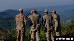 Paqeruajtës të NATO-s duke vëzhguar në Kosovë.