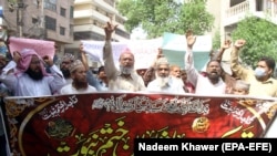 A banner reads in Arabic, 'I will sacrifice my parents for the Prophet's honor' at a protest to support the man who killed a man accused of blasphemy inside a court, in Hyderabad, on July 30.