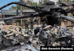 Trupele ucrainene inspectează un elicopter rus distrus la aerodromul Hostomel, din regiunea Kievului, 5 mai 2022.