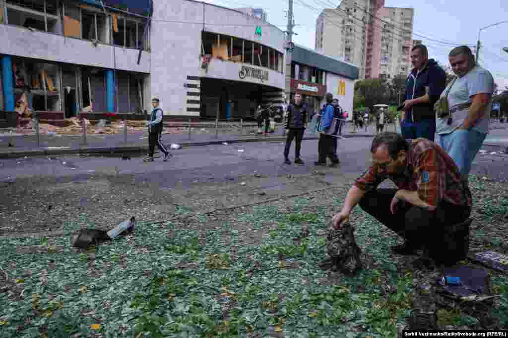 Një burrë inspekton një pjesë motori pas sulmeve ajrore ruse me dronë gjatë natës në Kiev, më 20-21 korrik. Në sfond shihet hyrja e stacionit të metrosë Lukyanivska.
