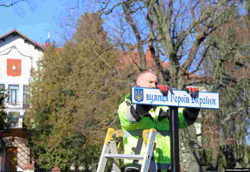 کارگری در حال نصب تابلوی خیابانی به زبان اوکراینی است که نام جاده‌ای منتهی به سفارت روسیه (که در پس‌زمینه قابل مشاهده است) را در ویلنیوس، لیتوانی، در مارس ۲۰۲۲ تغییر می‌دهد. این جاده اکنون خیابان «قهرمانان اوکراینی» نامیده می‌شود.