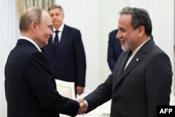 Russia's President Vladimir Putin (left) and Iranian Foreign Minister Abbas Araqchi shake hands during a meeting at the Kremlin in Moscow on June 23.