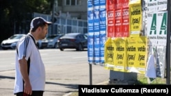 Un bărbat din Chișinău aruncă o privire pe afișele electorale ale partidelor politice din Moldova, înaintea alegerilor parlamentare care vor avea loc pe 28 septembrie 2025.