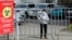 KAZAKHSTAN -- A woman wearing a protective face mask stands behind a fence placed around the residential building quarantined in response to the spread of coronavirus disease (COVID-19) in Almaty, March 24, 2020