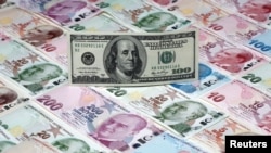 На иллюстрации изображена банкнота в 100 долларов, лежащая на банкнотах турецких лир различного достоинства, сделанная в Стамбуле, Турция, 7 января 2014 года.  