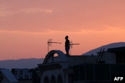 A man stands on the roof of a building while watching the horizon in Tehran on June 16. Iran's state broadcaster was briefly knocked off the air by an Israeli strike and explosions rang out across Tehran.